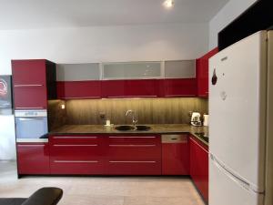 a red kitchen with a sink and a refrigerator at K2012 Kalina Grand-Tourist Apartments in Gdańsk