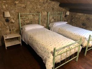 - 2 lits jumeaux dans une chambre avec un mur en pierre dans l'établissement Locanda Angelica, à Giarratana