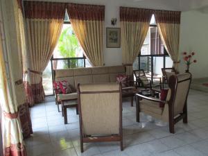 a living room with chairs and a couch and windows at Thilanka Beach Resort in Mount Lavinia