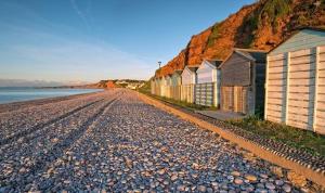 een rotsachtig strand met een rij huizen en de oceaan bij The Lawns B & B in Budleigh Salterton