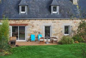 a stone house with a table and chairs in the yard at Maison luxueuse Louargat, jardin B in Louargat
