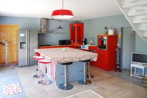 a kitchen with red cabinets and a counter with stools at Maison luxueuse Louargat, jardin B in Louargat