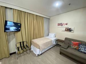 Habitación con cama, sofá y TV. en Nips 502 - Flat Executivo Zona Sul SP, en São Paulo