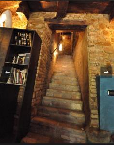 uma escadaria num edifício de tijolos com uma estante de livros em I CATARI ...nel cuore di Monforte d'Alba em Monforte dʼAlba