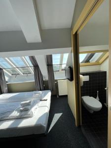 a hotel room with a bed, toilet and a window at Hotel Oostereiland in Hoorn