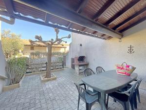 d'une terrasse avec une table, des chaises et un arbre. dans l'établissement Ref LS64: Maison 4-6 pers Les Hameaux de Camargue, à Saintes-Maries-de-la-Mer