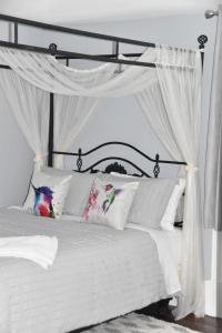 Cama blanca con cortinas y almohadas blancas en Seabank House Bed and Breakfast Hummingbird en Pictou