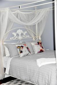 uma cama de dossel branca com cortinas e almofadas brancas em Seabank House Bed and Breakfast Hummingbird em Pictou