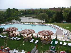 a large swimming pool with lounge chairs and a lake at Hotel Grivitsa in Pleven