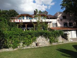 a house behind a stone wall with bushes at Hotel Grivitsa in Pleven