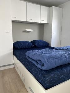 um quarto com uma cama com lençóis azuis e armários brancos em Vakantiepark Kijkduin - 884 em Haia