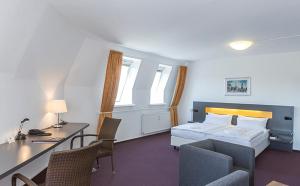 ein Hotelzimmer mit einem Bett, einem Schreibtisch und Stühlen in der Unterkunft Dietrich-Bonhoeffer-Hotel Berlin Mitte in Berlin