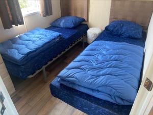 twee bedden in een kamer met blauwe kussens erop bij Vakantiepark Kijkduin - 870 in Den Haag