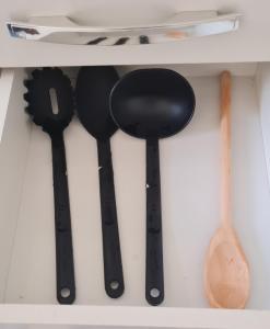 four black measuring spoons and a wooden spoon in a drawer at Ap confortável prox USP-HC fácil acesso Arena EUROBIKE , estacionamento e wifi 400 mega in Ribeirão Preto