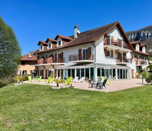 un grand bâtiment avec des chaises et des tables dans une cour dans l'établissement Hôtel les Bergeronnettes, à Champagneux