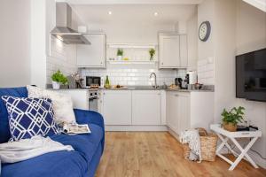 salon z niebieską kanapą i kuchnią w obiekcie Cobblers Cottage w mieście Sidmouth