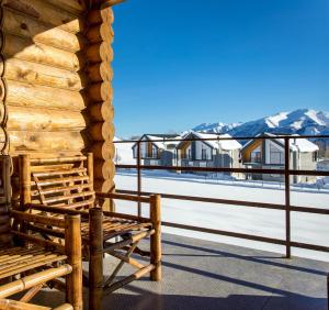 a wooden bench on a deck with mountains in the background at Snow Time Eco Chalet in Gudauri