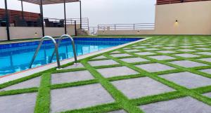 a swimming pool with grass on the ground next to it at Tripper Inn Hotel in Dammam