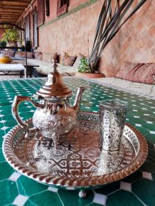 Riad le petit ksar في مكناس: صينية زجاجية مع وعاء الشاي والاكواب على طاولة