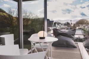 d'une table et de chaises blanches sur un balcon avec vue. dans l'établissement STEILLAGE - Design Moselsuiten mit Panoramablick und SPA, à Brauneberg