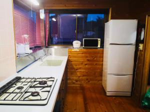 a kitchen with a stove and a white refrigerator at ＫＡＯＲＵ　ＩＮＮ in Minamiizu