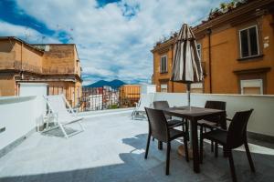 einen Tisch und Stühle auf einem Balkon mit Sonnenschirm in der Unterkunft Palazzo Settembrini 49 in Neapel