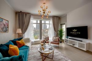 sala de estar con sofá azul y TV en Durrani Homes - Modern Living at Burj Views en Dubái