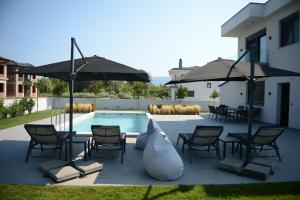 uma piscina com cadeiras e guarda-sóis ao lado de uma casa em Luxury Villa Plaka Litochoro em Plaka Litochorou