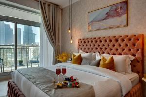 1 dormitorio con 1 cama grande y 2 copas de vino en Durrani Homes - Modern Living at Burj Views en Dubái