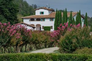 une maison au milieu d'une route aux fleurs roses dans l'établissement VIESCA Suites & Villas Il Borro Toscana, à Reggello