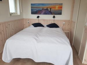 a bedroom with a white bed with a picture on the wall at Storstugan & Lillstugan Kullabygden in Ängelholm