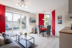 uma cozinha e sala de estar com cortinas vermelhas e uma mesa em Gorch-Fock Park 2 em Timmendorfer Strand