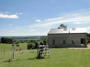 a barn with a swing set in a field at Holiday Home A Pas de Loup in La Roche-en-Ardenne