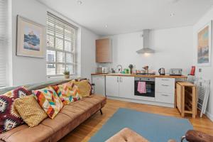 ein Wohnzimmer mit einem Sofa und einer Küche in der Unterkunft Boho Apartment In The Lanes in Brighton & Hove