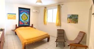a bedroom with a bed and two chairs in it at Studio lumineux avec vue sur la mer à Capesterre, 20 m², terrasse in Capesterre