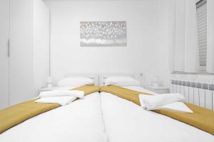 a white bedroom with two beds with yellow and white pillows at Rooms Studentsko Naselje Ivan Goran Kovačić in Rijeka