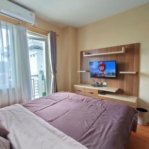 Kozy Room Sentul Tower Apartemen في بوغور: غرفة نوم بسرير وتلفزيون بشاشة مسطحة