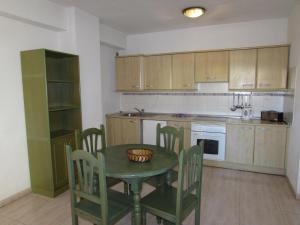 una cocina con mesa verde, sillas y barra en Apartamentos Alta, en Puerto de la Cruz