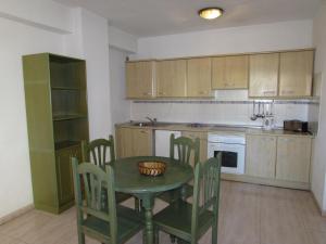 a kitchen with a green table and chairs and a counter at Apartamentos Alta in Puerto de la Cruz