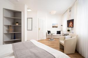 a white bedroom with a bed and a living room at Hotel Haus am Park in Borkum