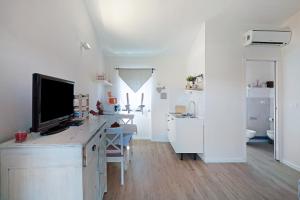 Habitación blanca con escritorio y TV. en Rosadimaggio Violetta, en Arcola