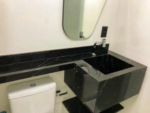 a bathroom with a sink and a mirror and a toilet at Shopping Piratas, vista para o mar, estacionamento in Angra dos Reis