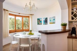 a kitchen with a white table and chairs and a chandelier at Villa Armonia in Son Bou
