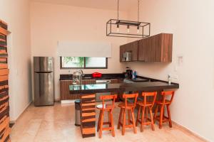 a kitchen with a black counter and orange bar stools at Villa with ocean view, pool, restaurant and rooftop in Isla Mujeres