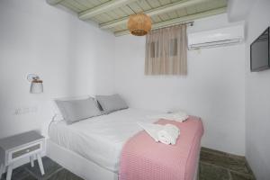 a bedroom with a white bed with a pink ottoman at SERIFOS BELLA VISTA 1 in Livadi