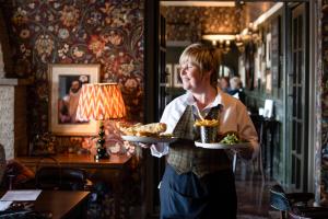 a woman holding a plate of food in a restaurant at The Black Swan - The Inn Collection Group in Helmsley