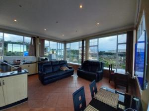 a living room with couches and a kitchen with windows at La Lucia Ridge Self Catering Penthouse Environment in Durban