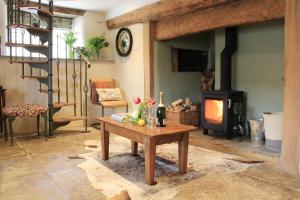 a living room with a wood stove and a table at Bramley Cottage at Stepps House in Broadway