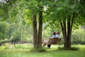 deux femmes assises sur un banc de parc entre arbres dans l'établissement Vakantieverblijf Volmolen B&B, à Maaseik