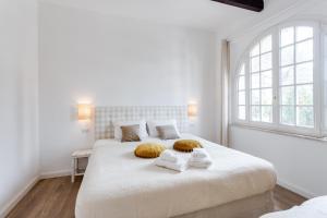 a white bedroom with two beds and a window at Maison d'Orange - La Pinede in Saint-Tropez